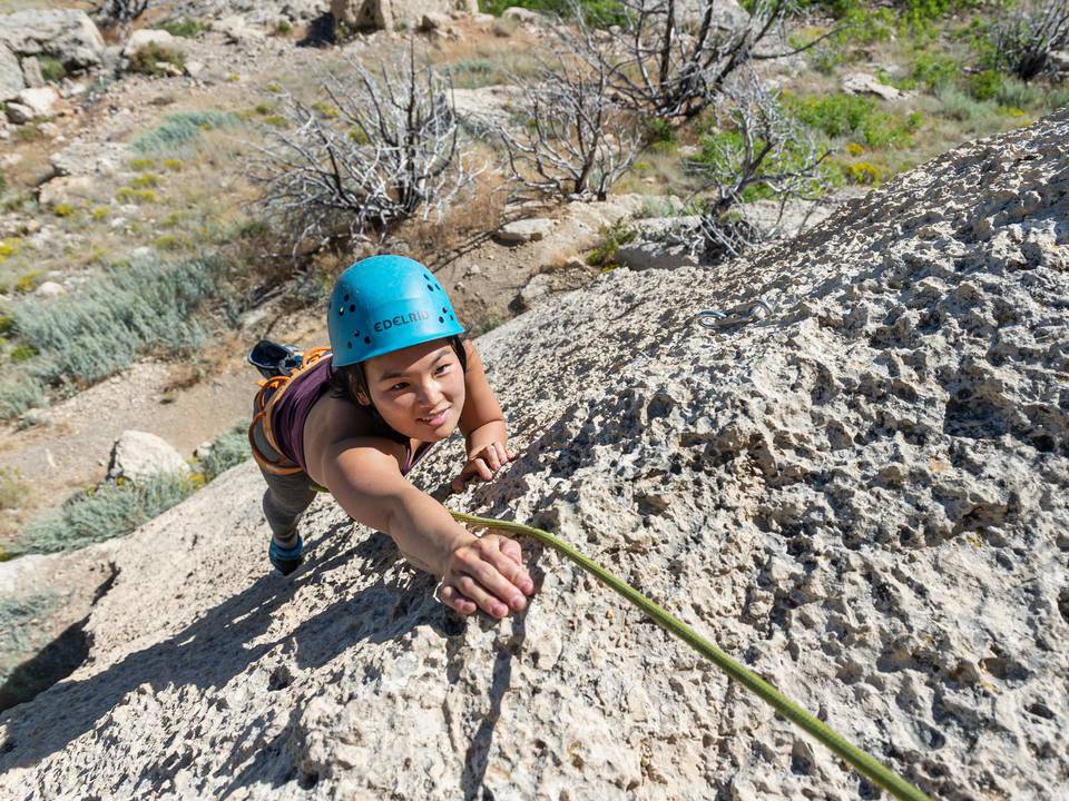 Sporty young woman dressed in rock climbing outfit training at